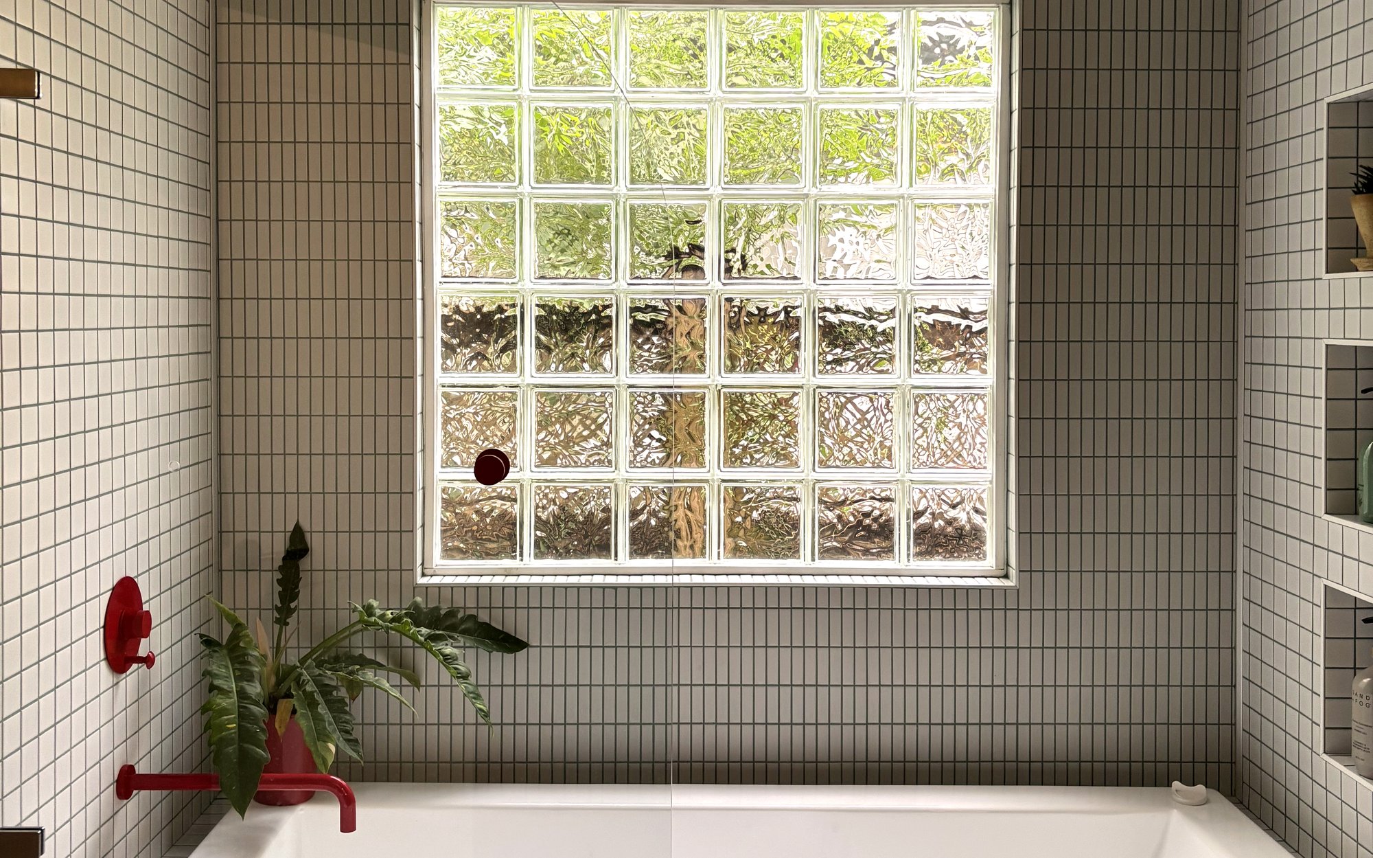 Solomon St. &mdash; tiled bath with drop-in tub, glass block window, and red fixtures